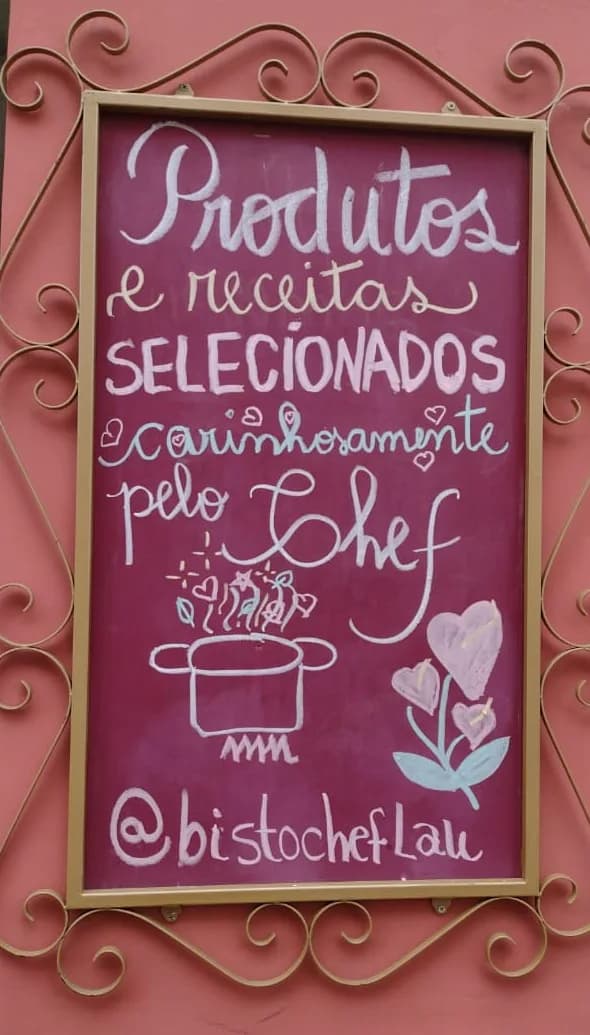 Quadro de giz do Bistrô Chef Lau em moldura de ferro dourada: "Produtos e receitas selecionados carinhosamente pelo Chef." Ilustração de uma panela fumegante e um antúrio.